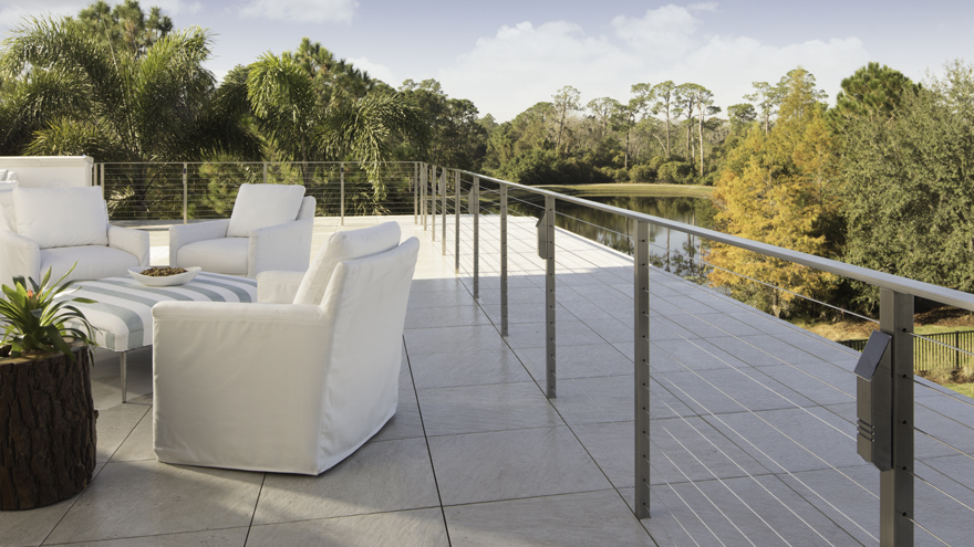 Elegant miami wire railing system with landscape lighting. Patio railing system with core drill mounted posts.