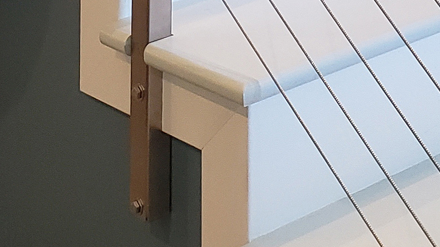 This railing side mount railing post is recessed into the wood stair with a notched decking edge.